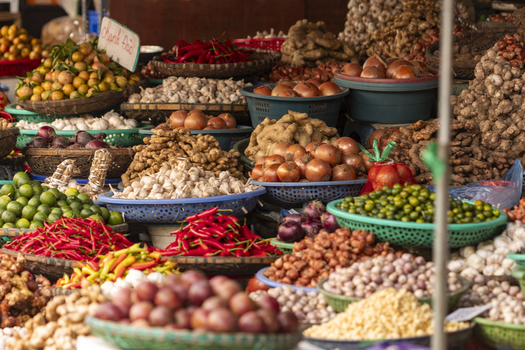 View of a vibrant market stall filled with baskets of fresh produce including red chili peppers garlic onions and ginger in Hanoi Ha Noi Vietnam.