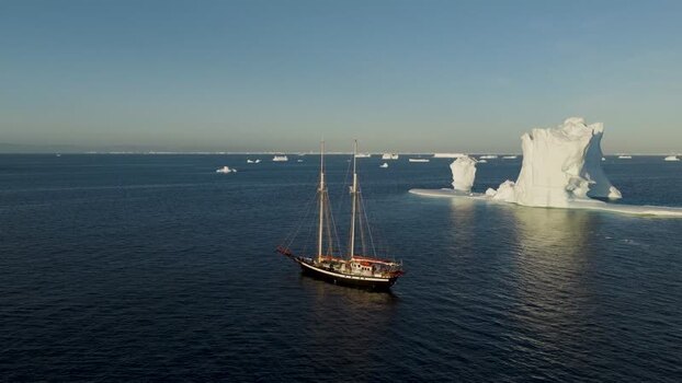 Aerial view of a sailing ship near an arch iceberg Greenland. Aerial view of a sailing ship near an arch iceberg Greenland.