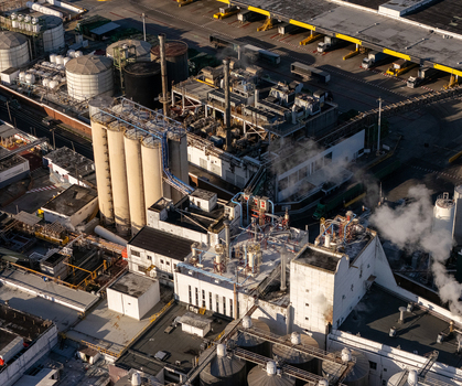 Aerial view of a beer industrial complex featuring large storage silos complex piping systems and industrial buildings with steam rising from vents in Santo Domingo Dominican Republic. Aerial view of a beer industrial complex featuring large storage silos complex piping systems and industrial buildings with steam rising from vents in Santo Domingo Dominican Republic.
