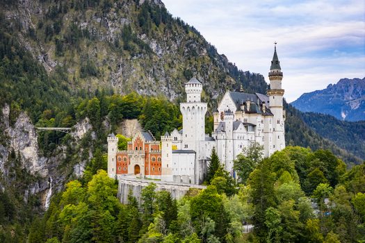Aerial view of the majestic Neuschwanstein Castle perched atop a verdant hill its white towers contrasting against the deep green forest backdrop Füssen Bayern Germany. Aerial view of the majestic Neuschwanstein Castle perched atop a verdant hill its white towers contrasting against the deep green forest backdrop Füssen Bayern Germany.