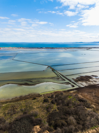 Aerial view of the geometric salt pans of Lake Atanasovsko with the Black Sea coast under a blue sky in Burgas Burgas Bulgaria. Aerial view of the geometric salt pans of Lake Atanasovsko with the Black Sea coast under a blue sky in Burgas Burgas Bulgaria.