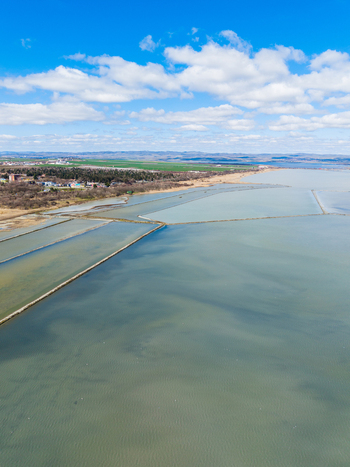 Aerial view of Lake Atanasovsko with geometric salt pans and narrow dikes under a blue sky with clouds in Burgas Burgas Bulgaria. Aerial view of Lake Atanasovsko with geometric salt pans and narrow dikes under a blue sky with clouds in Burgas Burgas Bulgaria.