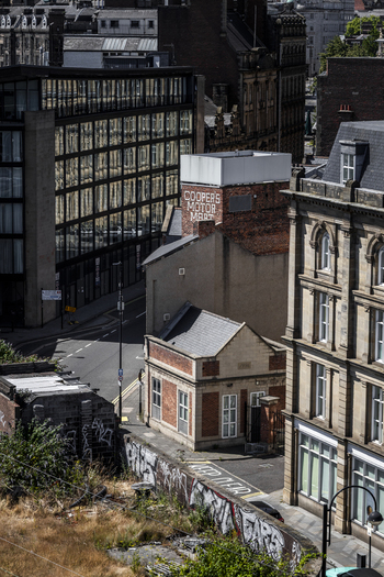 Aerial view of a historic brick building with Cooper s Motor Mart signage situated among modern glass architecture and traditional stone buildings in Newcastle upon Tyne England United Kingdom. Aerial view of a historic brick building with Cooper s Motor Mart signage situated among modern glass architecture and traditional stone buildings in Newcastle upon Tyne England United Kingdom.