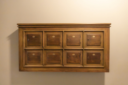View of a vintage wooden cabinet with eight numbered compartments mounted on a plain wall in Gdansk Pomeranian Voivodeshi Poland. View of a vintage wooden cabinet with eight numbered compartments mounted on a plain wall in Gdansk Pomeranian Voivodeshi Poland.