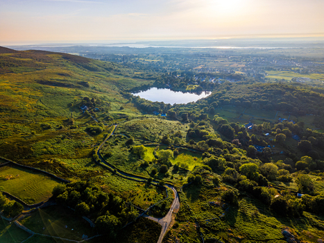 Aerial view of Llyn Padarn surrounded by lush green hills stone walls and a winding road in the golden hour light in Cwm y glo Wales United Kingdom. Aerial view of Llyn Padarn surrounded by lush green hills stone walls and a winding road in the golden hour light in Cwm y glo Wales United Kingdom.