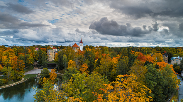 Aerial view of Cesis Castle surrounded by vibrant autumn foliage historic stone towers and a park pond under a dramatic cloudy sky in Cesis Cesis Municipality Latvia. Aerial view of Cesis Castle surrounded by vibrant autumn foliage historic stone towers and a park pond under a dramatic cloudy sky in Cesis Cesis Municipality Latvia.