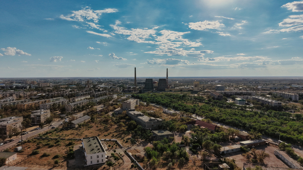Aerial view of Baikonur Cosmodrome and surrounding industrial and residential areas with chimneys and trees under a blue sky in Karmakshy District Kyzylorda Region Kazakhstan.