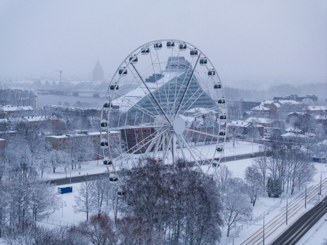 Aerial view of a large Ferris wheel standing in a snow covered park with the National Library of Latvia in the background in Riga Latvia. Aerial view of a large Ferris wheel standing in a snow covered park with the National Library of Latvia in the background in Riga Latvia.