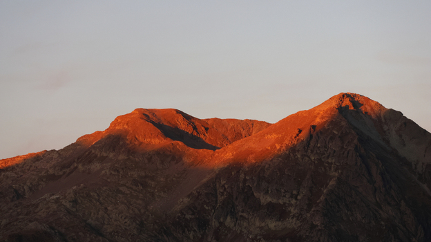 View of the Bel Oiseau mountain peak illuminated by the warm light of the golden hour with rugged rocky slopes in Finhaut Valais Switzerland. View of the Bel Oiseau mountain peak illuminated by the warm light of the golden hour with rugged rocky slopes in Finhaut Valais Switzerland.