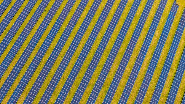 Aerial view of rows of solar panels installed in a field with green grass in Dorset England United Kingdom. Aerial view of rows of solar panels installed in a field with green grass in Dorset England United Kingdom.