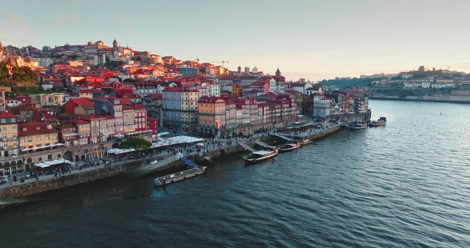 Aerial view of the historic Ribeira district along the Douro River with colorful buildings traditional rabelo boats and stone embankments in Porto Porto Portugal. Aerial view of the historic Ribeira district along the Douro River with colorful buildings traditional rabelo boats and stone embankments in Porto Porto Portugal.