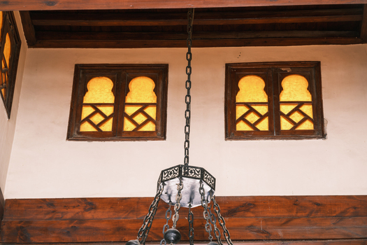 View of the traditional arched windows with geometric lattice and a hanging metal chandelier inside the historic Al Azhar Mosque Cairo Egypt. View of the traditional arched windows with geometric lattice and a hanging metal chandelier inside the historic Al Azhar Mosque Cairo Egypt.
