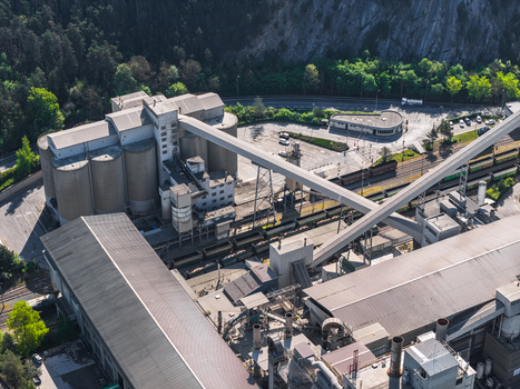 Aerial view of an industrial facility featuring large cylindrical silos extensive conveyor belt systems and railway tracks with freight cars in Prague Prague Czechia.