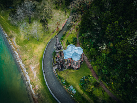 Aerial view of a gothic church standing proud in the landscape juxtaposed against the serene lake and the verdant forest Furnas Azores Portugal.