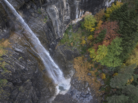 Aerial view of the Pyrenees waterfall cascading down a steep rocky cliff surrounded by vibrant autumn foliage in Spain. Aerial view of the Pyrenees waterfall cascading down a steep rocky cliff surrounded by vibrant autumn foliage in Spain.
