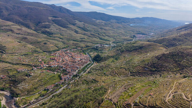Aerial view of a compact town nestled in a valley its terracotta roofs contrasting with the verdant slopes and rugged peaks Cabezuela del Valle Extremadura Spain.