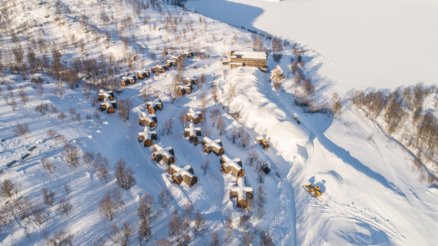 Aerial view of the Kirkenes Snowhotel featuring unique cross shaped cabins in a snow covered landscape with bare trees and a frozen lake in Kirkenes Finnmark Norway. Aerial view of the Kirkenes Snowhotel featuring unique cross shaped cabins in a snow covered landscape with bare trees and a frozen lake in Kirkenes Finnmark Norway.