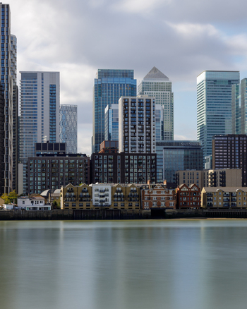 View of the modern skyscrapers and glass towers of the Canary Wharf business district rising above the River Thames in London England United Kingdom. View of the modern skyscrapers and glass towers of the Canary Wharf business district rising above the River Thames in London England United Kingdom.