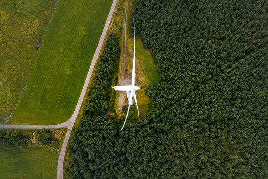 Aerial view of Hog Jaeren vindkraftverk wind turbine surrounded by dense pine forest and green agricultural fields in Ha Municipality Rogaland Norway.