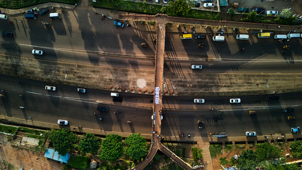 Aerial view of a pedestrian bridge spanning a busy highway with flowing traffic and long shadows in Kaduna Kaduna Nigeria. Aerial view of a pedestrian bridge spanning a busy highway with flowing traffic and long shadows in Kaduna Kaduna Nigeria.