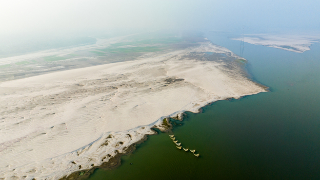 Aerial view of the riverbank with sandbars and small traditional boats on the water in Pabna Rajshahi Division Bangladesh.