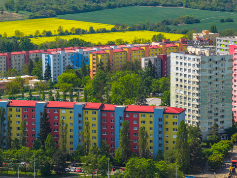Aerial view of colorful residential apartment blocks with red roofs surrounded by lush green trees and vibrant yellow rapeseed fields in Prague Prague Czechia.
