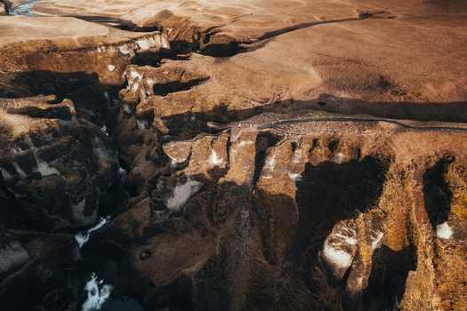 Aerial view of the rugged Fjadrargljufur canyon with its steep winding walls carved by a glacial river a tapestry of dark shadows and light kissed peaks Fjadrargljufur Iceland. Aerial view of the rugged Fjadrargljufur canyon with its steep winding walls carved by a glacial river a tapestry of dark shadows and light kissed peaks Fjadrargljufur Iceland.