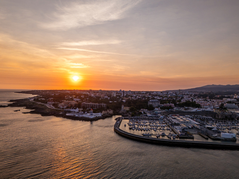 Aerial view of the marina and coastline of Cascais at sunset with boats docked in the harbor and the golden sun setting over the Atlantic Ocean in Cascais Lisboa Portugal. Aerial view of the marina and coastline of Cascais at sunset with boats docked in the harbor and the golden sun setting over the Atlantic Ocean in Cascais Lisboa Portugal.