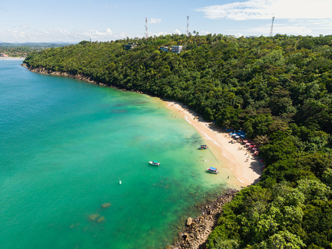 Aerial view of Jungle Beach with people on the sand turquoise water small boats and lush green forest on the coastline in Unawatuna Sri Lanka. Aerial view of Jungle Beach with people on the sand turquoise water small boats and lush green forest on the coastline in Unawatuna Sri Lanka.