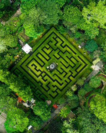 Aerial view of the square hedge maze at Coban Rondo Waterfall surrounded by lush green trees and tropical foliage in Kecamatan Pujon Jawa Timur Indonesia. Aerial view of the square hedge maze at Coban Rondo Waterfall surrounded by lush green trees and tropical foliage in Kecamatan Pujon Jawa Timur Indonesia.