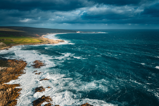 Aerial view of Canal Rocks Bridge with dramatic storm clouds crashing waves against rocky outcrops and green vegetation in Yallingup Western Australia Australia.