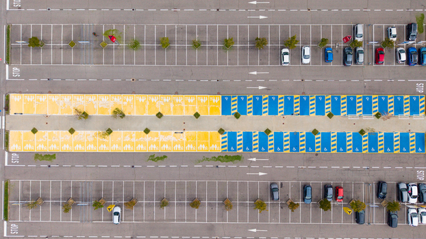 Aerial view of a parking lot featuring designated spaces for families and people with disabilities marked with yellow and blue paint in San Giuliano Milanese Lombardy Italy.