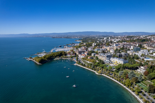 Aerial view of Ouchy district on the shores of Lake Geneva with its harbor historic buildings and lush trees in Lausanne Vaud Switzerland.
