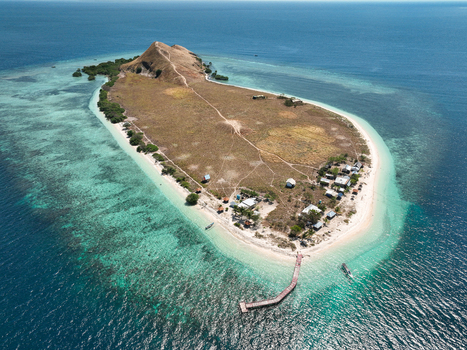 Aerial view of Pulau Kenawa with its grassy hills sandy beaches turquoise coral reefs and a wooden pier extending into the clear water in Poto Tano West Nusa Tenggara Indonesia. Aerial view of Pulau Kenawa with its grassy hills sandy beaches turquoise coral reefs and a wooden pier extending into the clear water in Poto Tano West Nusa Tenggara Indonesia.
