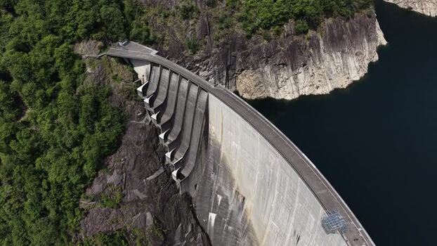 Aerial view of Verzasca Dam and lush green forests Switzerland.