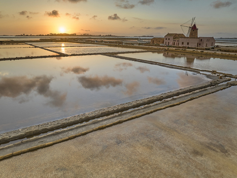 Aerial view of Saline dello Stagnone featuring traditional windmills and salt pans reflecting the golden sunset sky in Marsala Sicilia Italy. Aerial view of Saline dello Stagnone featuring traditional windmills and salt pans reflecting the golden sunset sky in Marsala Sicilia Italy.
