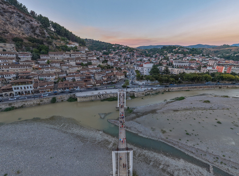 Aerial view of the historic town of Berat with its traditional Ottoman style houses the Osum River and a pedestrian suspension bridge in Berat Berat County Albania.