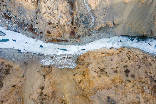 Aerial view of a glacial river snaking through the rugged sun kissed terrain of Chapursan Valley its icy waters a stark contrast to the arid landscape Hunza Nagar Pakistan. Aerial view of a glacial river snaking through the rugged sun kissed terrain of Chapursan Valley its icy waters a stark contrast to the arid landscape Hunza Nagar Pakistan.