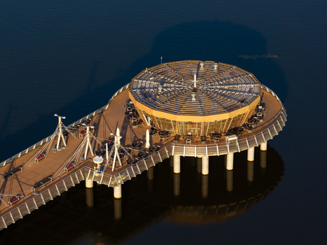 Aerial view of the modern circular pier restaurant extending over the Vistula river with a wooden deck and seating areas in Plock Masovian Voivodeship Poland. Aerial view of the modern circular pier restaurant extending over the Vistula river with a wooden deck and seating areas in Plock Masovian Voivodeship Poland.