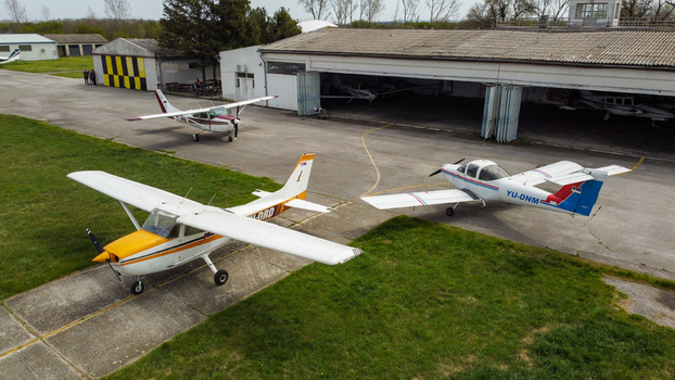 Serbia 11 April 2021 Aerial view of small light aircraft parked on the tarmac in front of a hangar at a local airfield. Serbia 11 April 2021 Aerial view of small light aircraft parked on the tarmac in front of a hangar at a local airfield.