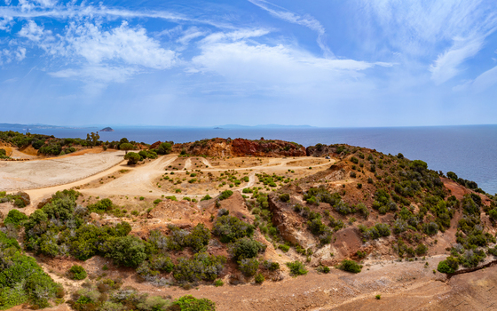 Aerial view of the historic iron mine area with distinctive reddish soil and rocky terrain near Laghetto delle conche overlooking the Mediterranean Sea in Rio Marina Toscana Italy.