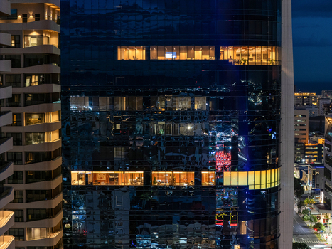Aerial view of a modern glass skyscraper at night with illuminated office windows in Santo Domingo Distrito Nacional Dominican Republic. Aerial view of a modern glass skyscraper at night with illuminated office windows in Santo Domingo Distrito Nacional Dominican Republic.