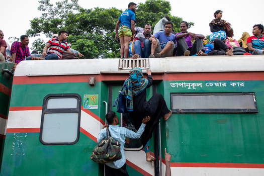 Dhaka Bangladesh 15 June 2018 View of people sitting on the roof of a train while a woman climbs through a window at Airport Railway Station. Dhaka Bangladesh 15 June 2018 View of people sitting on the roof of a train while a woman climbs through a window at Airport Railway Station.