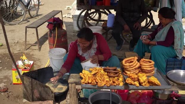 View of a woman frying traditional snacks at a street stall in Nepal. View of a woman frying traditional snacks at a street stall in Nepal.