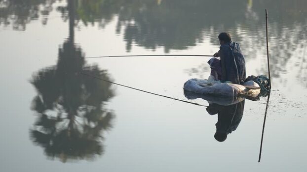 View of a fisherman on a small raft in a calm lake Bangladesh.