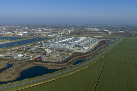 Aerial view of the Google data center surrounded by solar panels and vast green fields under a clear blue sky Winschoten Groningen Netherlands.