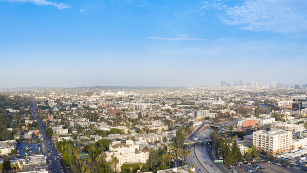 Aerial view of the urban landscape with residential buildings a highway and the distant city skyline under a clear blue sky in Los Angeles California United States.