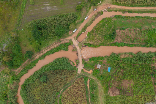Aerial view of a river flowing through agricultural fields and crossing a bridge in Butaleja Eastern Region Uganda. Aerial view of a river flowing through agricultural fields and crossing a bridge in Butaleja Eastern Region Uganda.