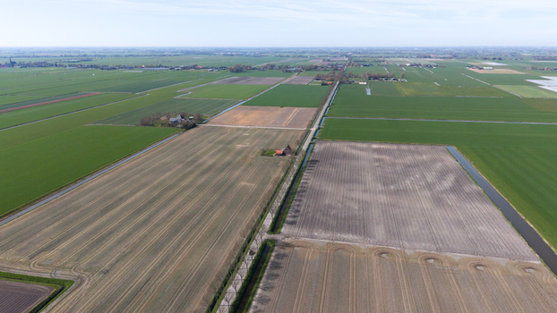 Aerial view of neatly patterned fields a patchwork of greens and browns divided by narrow waterways reflecting the sky Lambertschaag North Holland Netherlands. Aerial view of neatly patterned fields a patchwork of greens and browns divided by narrow waterways reflecting the sky Lambertschaag North Holland Netherlands.