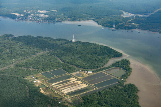 Aerial view of the Johor River winding through lush green forests and aquaculture ponds in Johor Bahru Johor Malaysia.